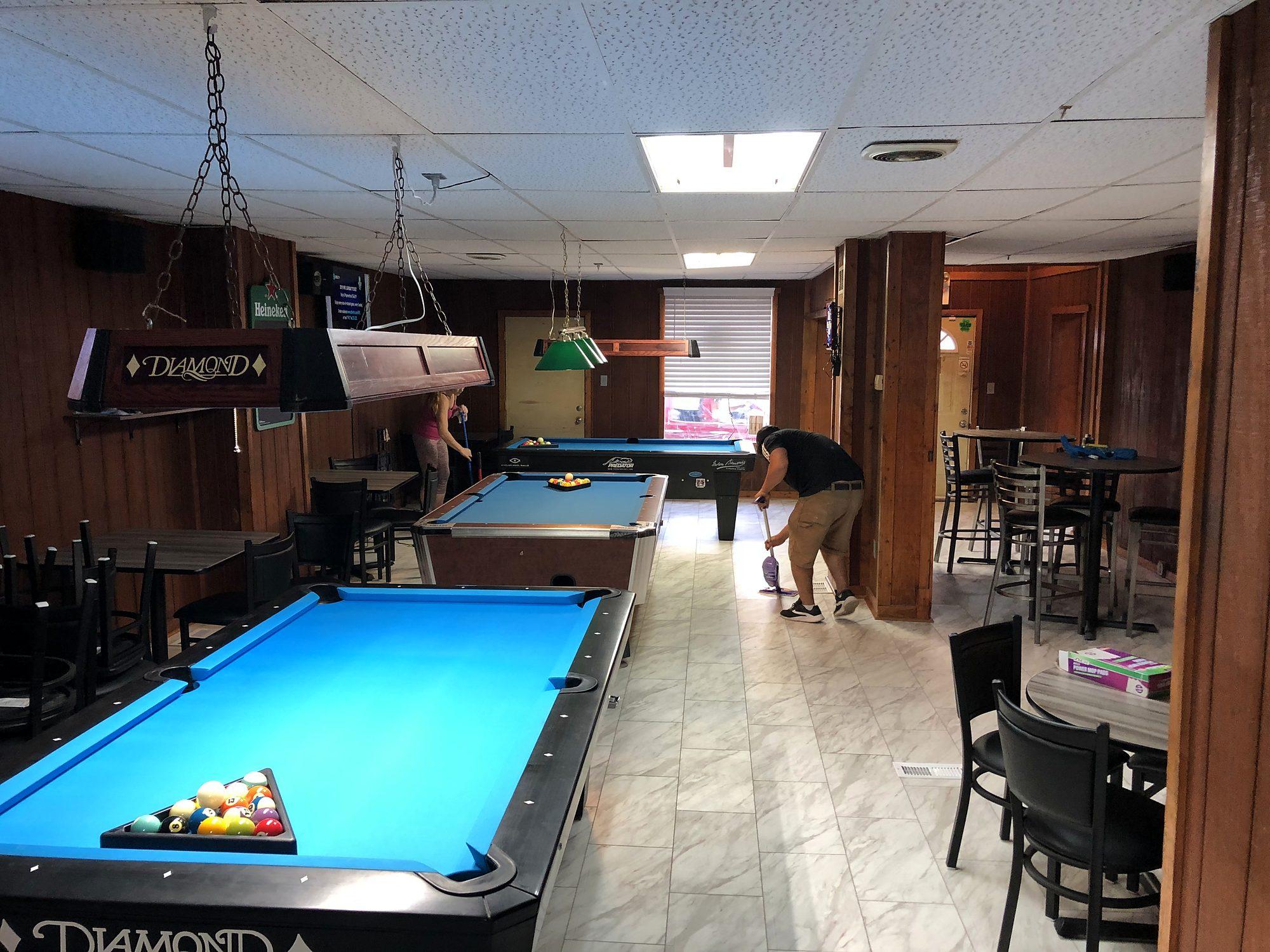 Renovated game room with new tile flooring, pool tables and bar seating