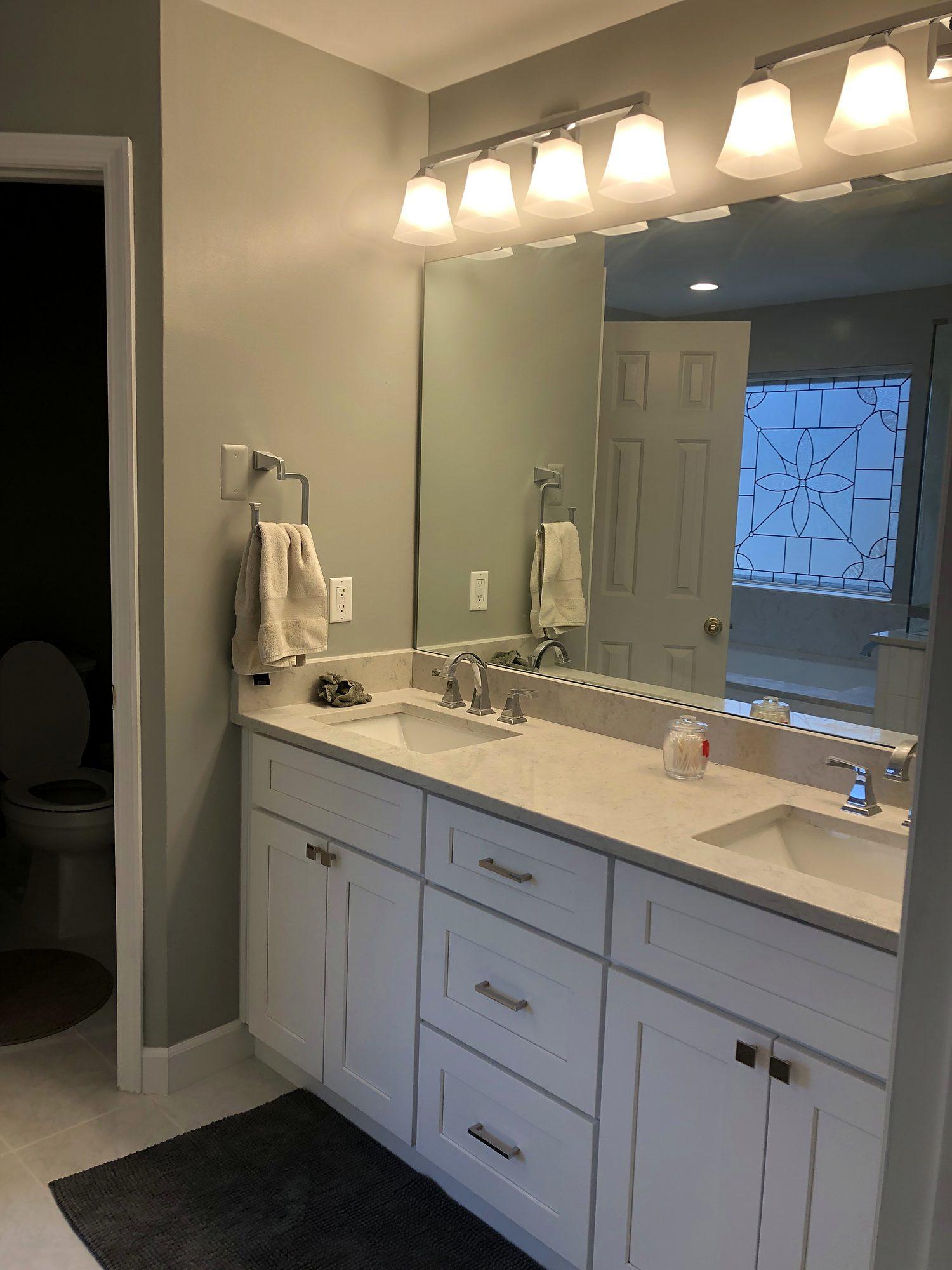 Bathroom remodel with white shaker double vanity, quartz top and vanity lighting