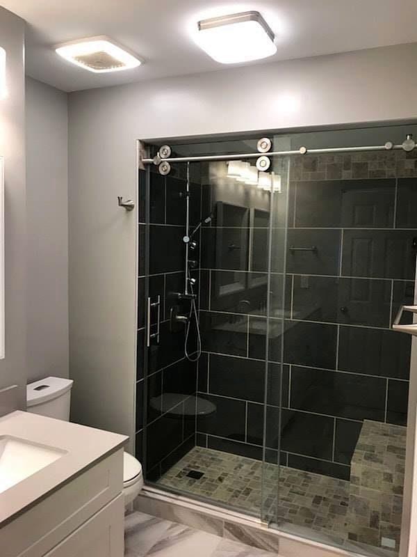Walk-in shower with charcoal tile walls, built-in bench and frameless sliding glass door