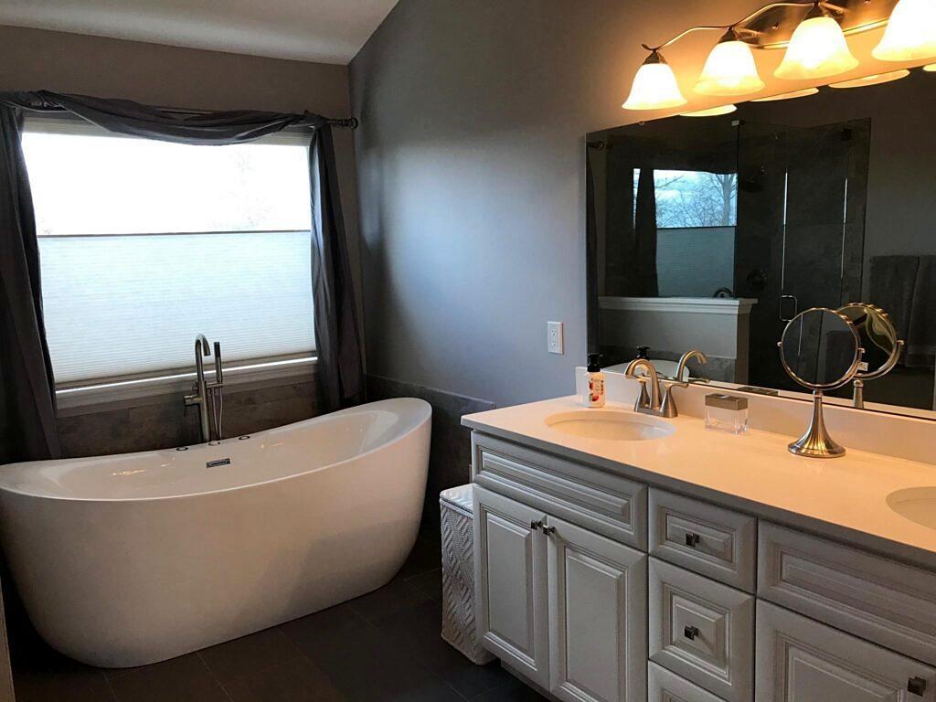 Bathroom remodel with freestanding soaking tub, white double vanity and modern fixtures