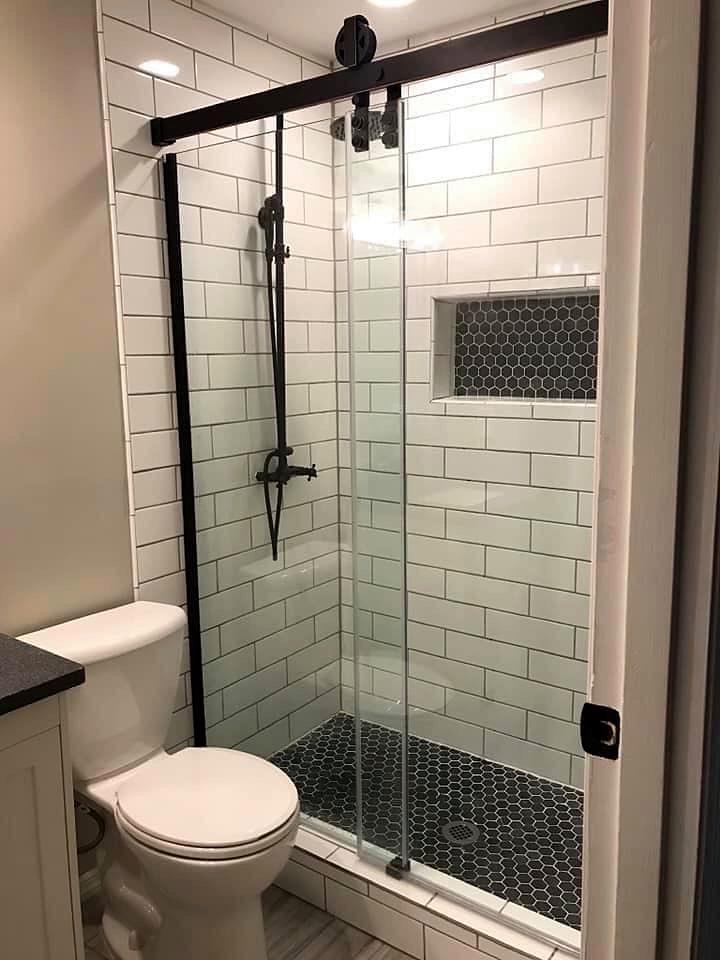 Small bathroom remodel with white subway tile shower, hex niche and black-framed glass door