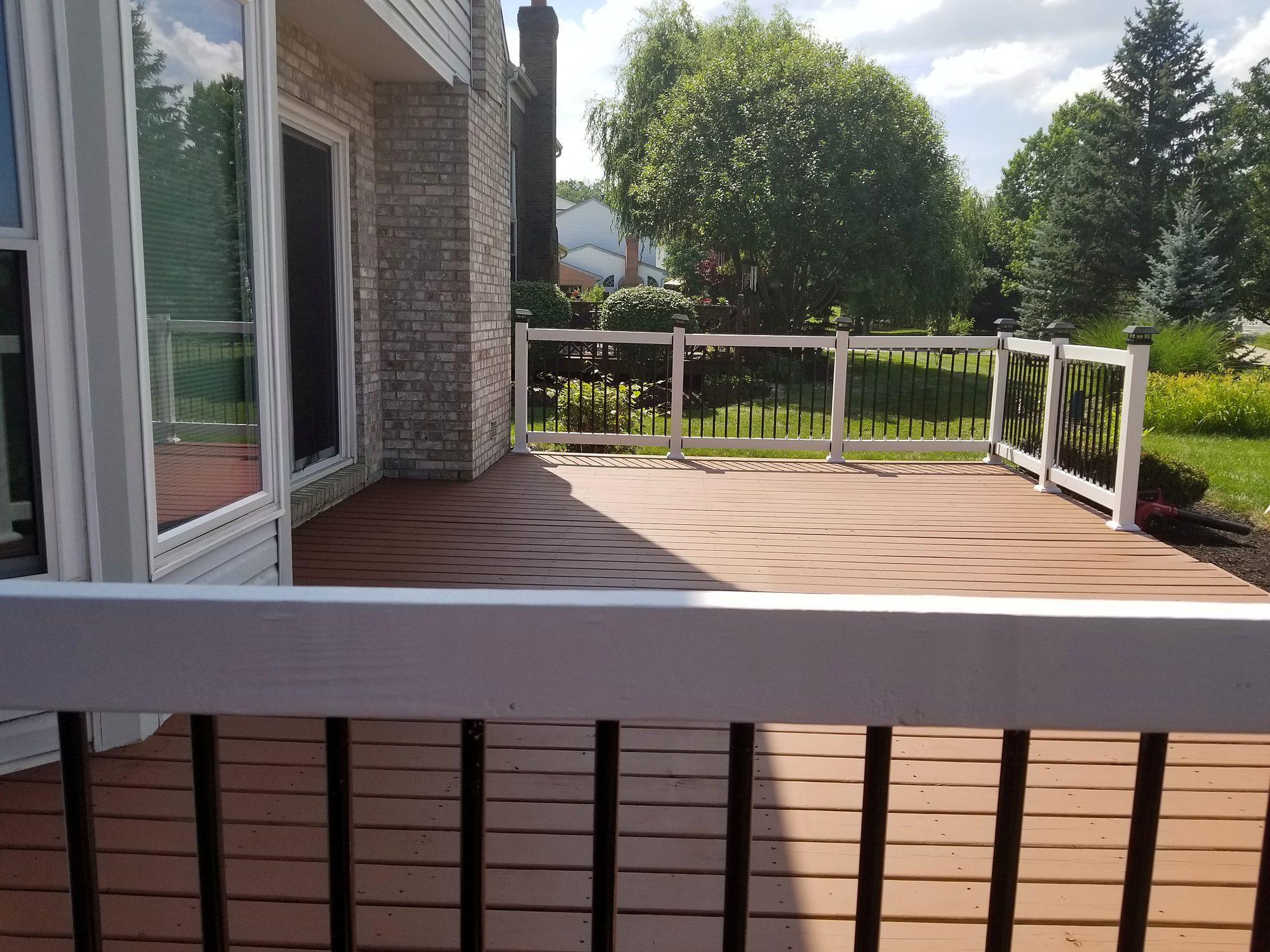 Composite deck with white vinyl railing and black balusters overlooking a landscaped backyard
