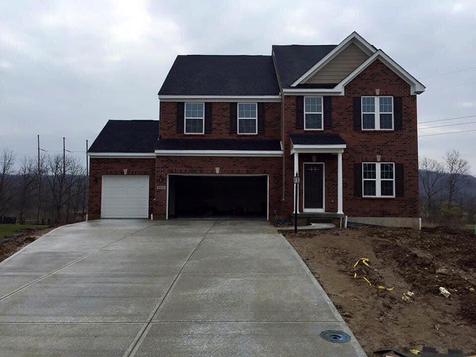 New broom-finish concrete driveway with control joints leading to a two-car garage