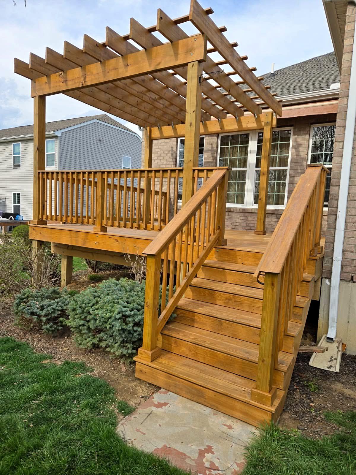 Wood deck with a pergola, railings and a wide stairway down to the yard