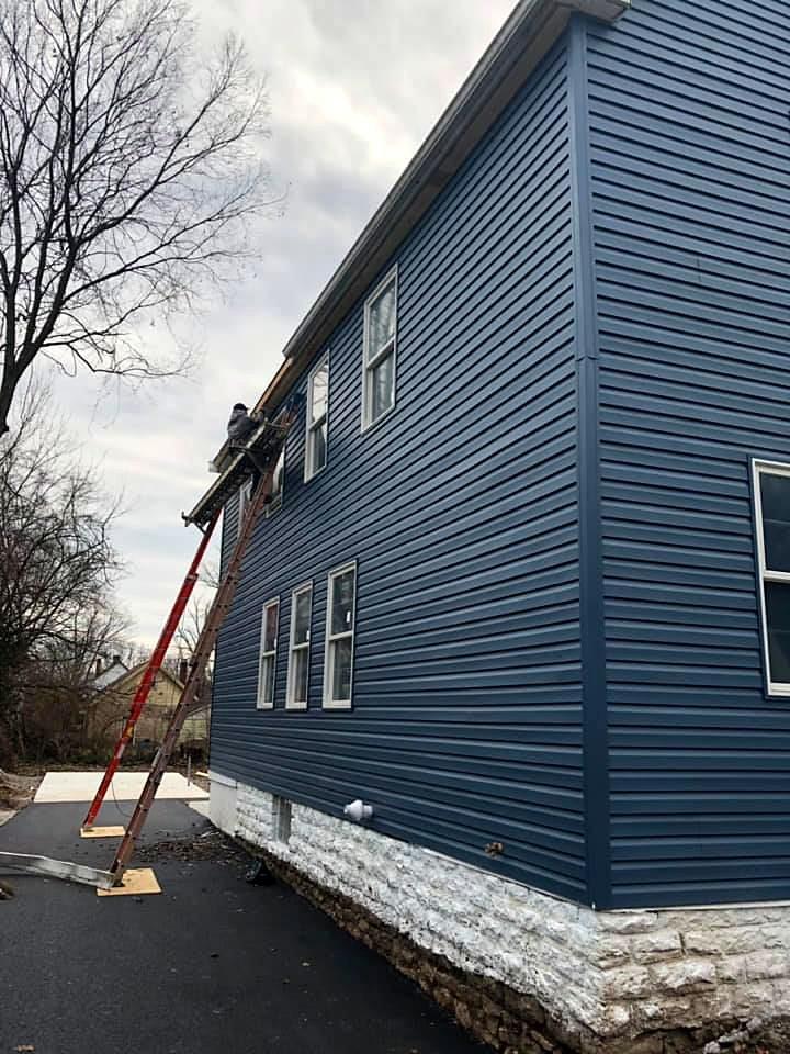 Exterior renovation with new blue vinyl siding and stone foundation