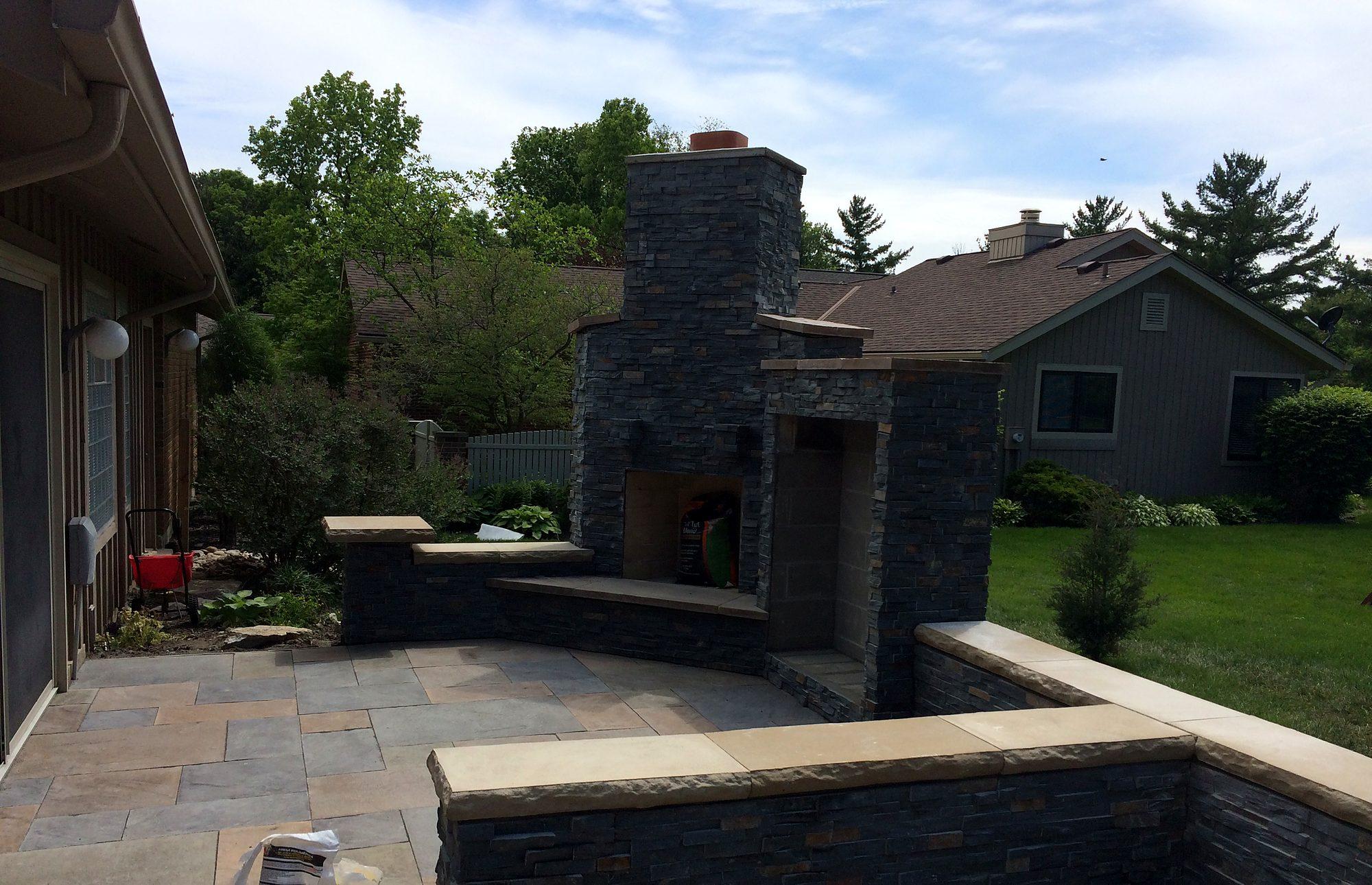 Flagstone patio with stone outdoor fireplace and seat walls