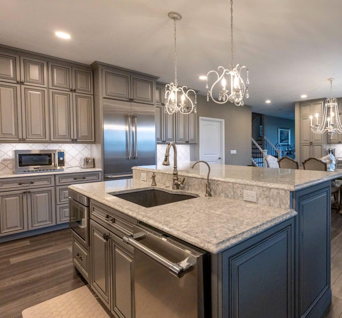 Gray kitchen island with an undermount sink, granite countertop and crystal chandeliers