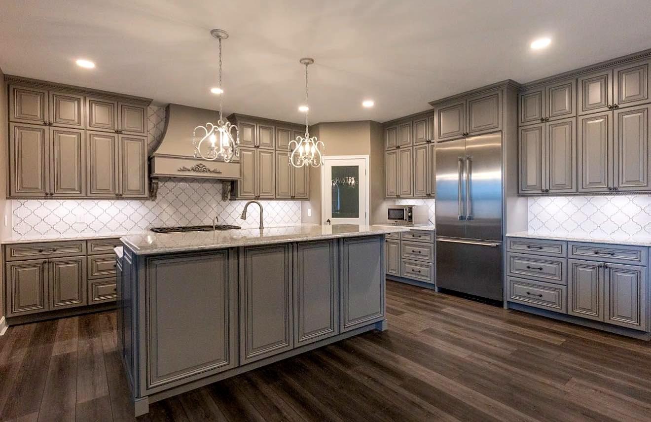 Open kitchen remodel with blue-gray center island, quartz countertops, crystal pendant lights and luxury vinyl plank flooring