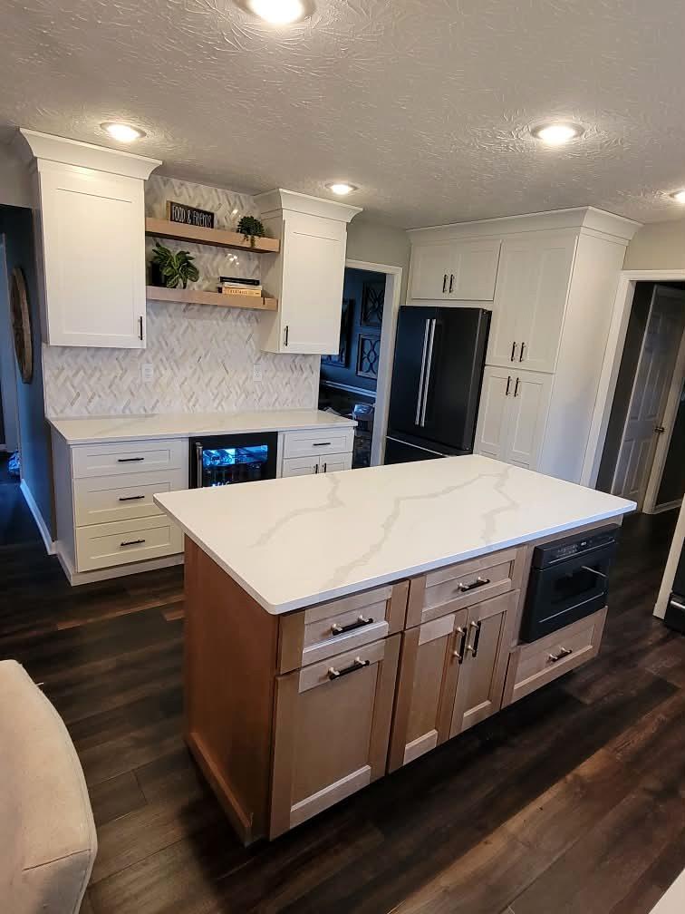 Kitchen island with stained wood cabinetry and a white quartz top, plus floating shelves and a built-in beverage fridge