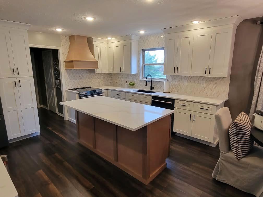 White shaker kitchen with a stained wood range hood, stained wood island with a white quartz top and a herringbone backsplash