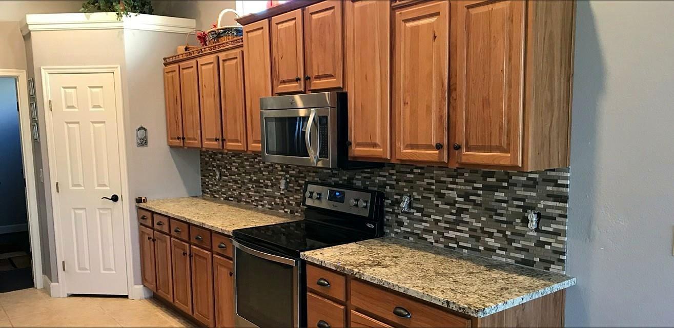 Kitchen with stained wood cabinets, granite countertops, glass mosaic tile backsplash and stainless appliances