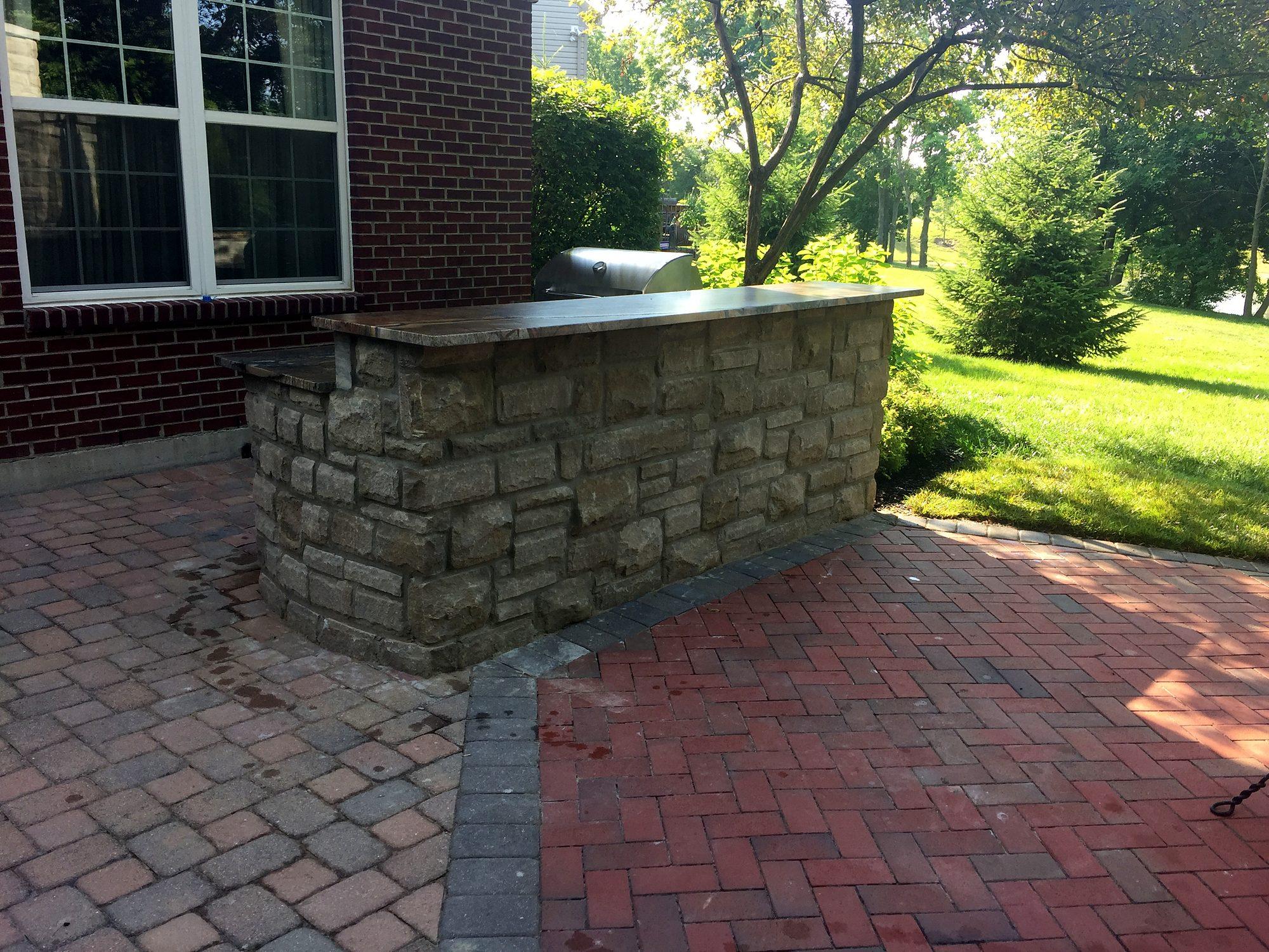 Stone veneer outdoor bar on a brick paver patio