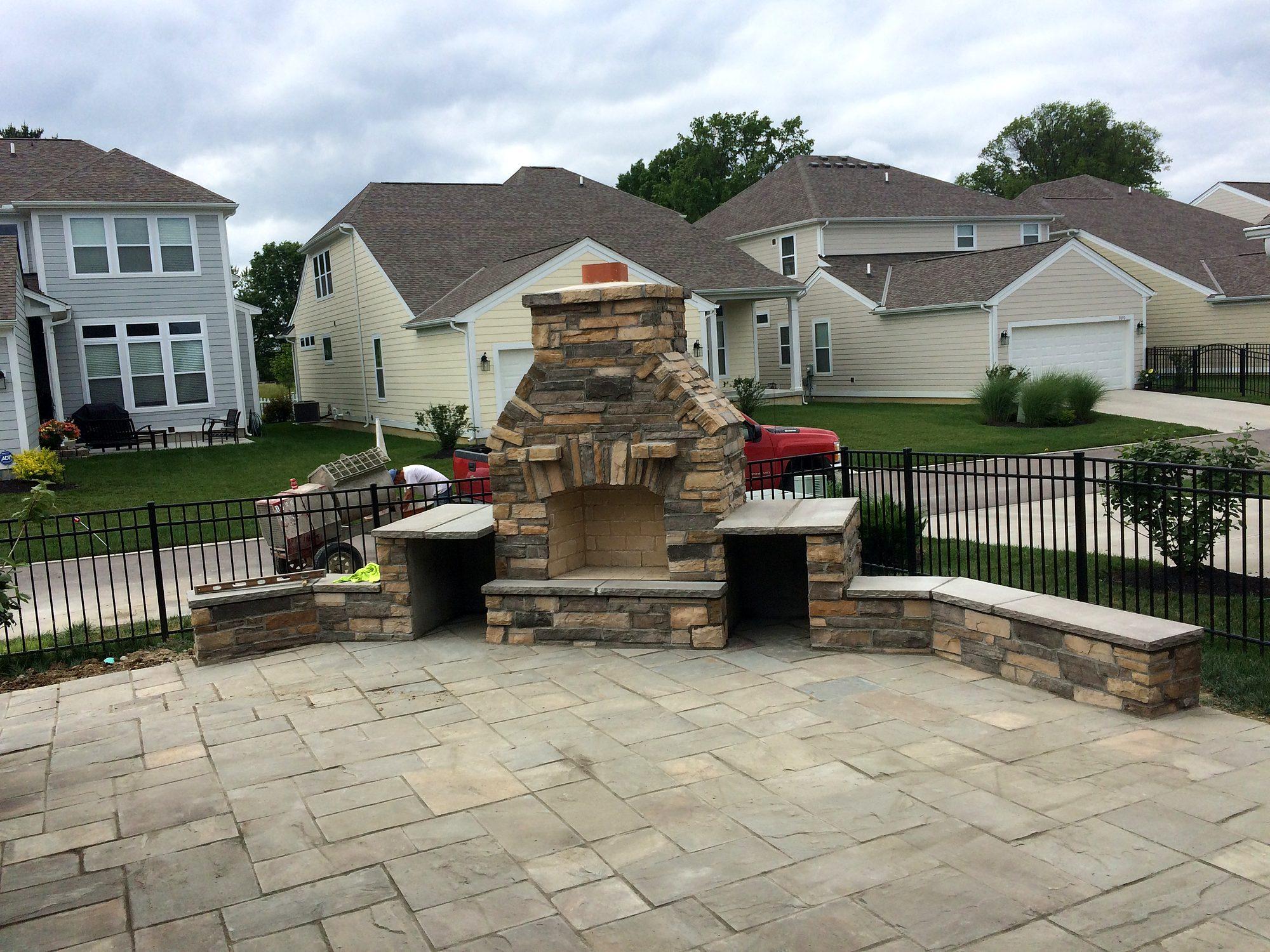 Outdoor living space with stone fireplace, seat walls and large paver patio