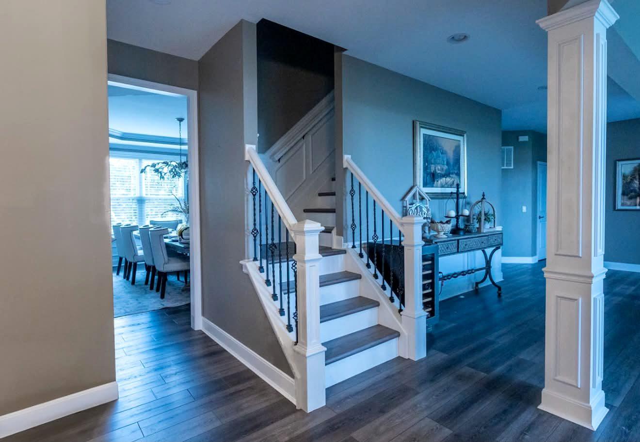 Entry staircase with white painted risers and balusters, black spindles and a paneled column