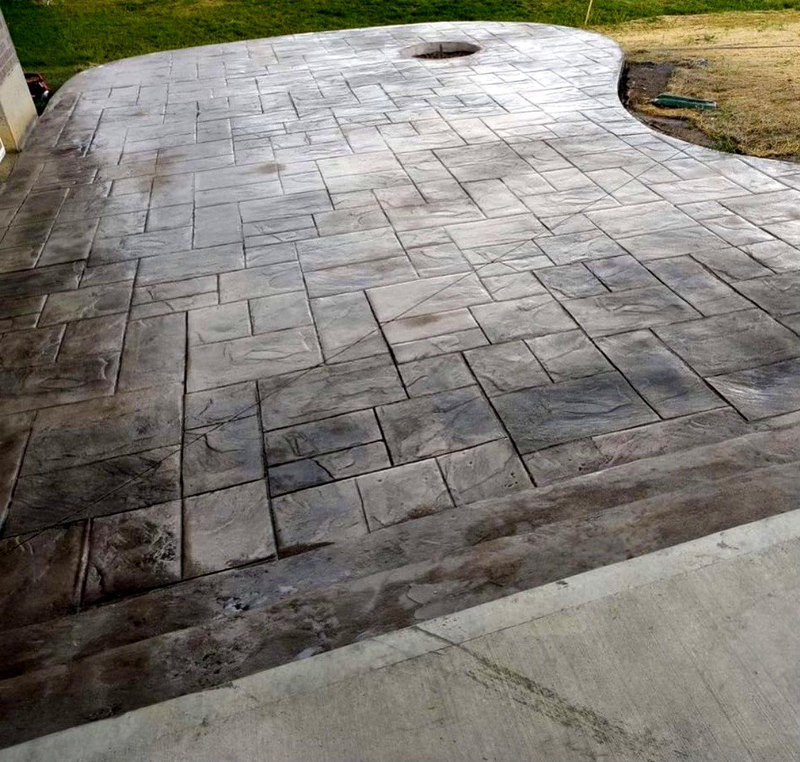 Large stamped concrete patio in an ashlar slate pattern with a curved edge