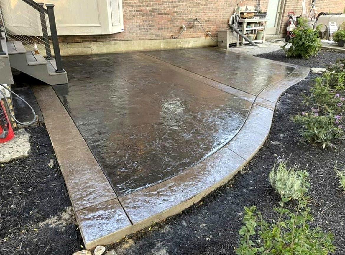 Curved stamped concrete walkway with a smooth contrasting border through landscaped beds