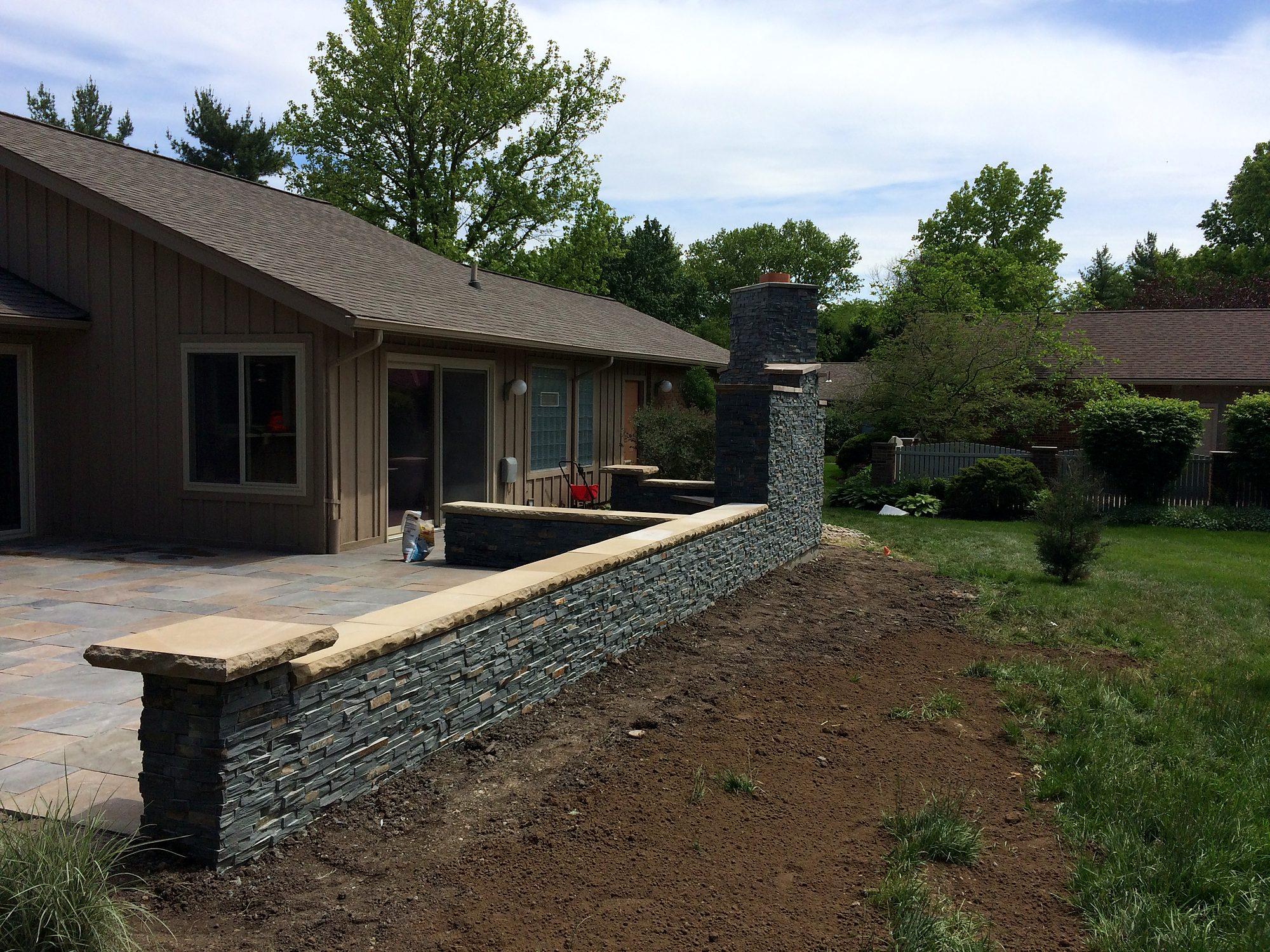 Natural stone seat wall with cap stones bordering a paver patio